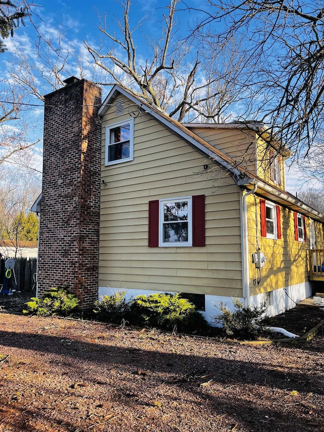 view of side of home featuring a chimney and fence