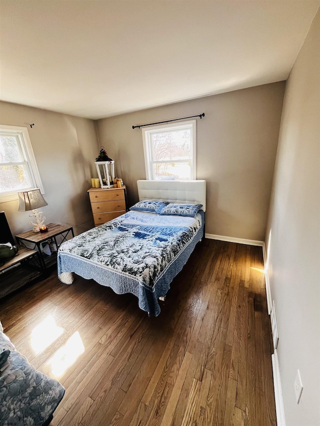 bedroom featuring visible vents, multiple windows, baseboards, and hardwood / wood-style floors