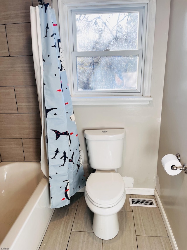 full bathroom with toilet, baseboards, visible vents, and a healthy amount of sunlight