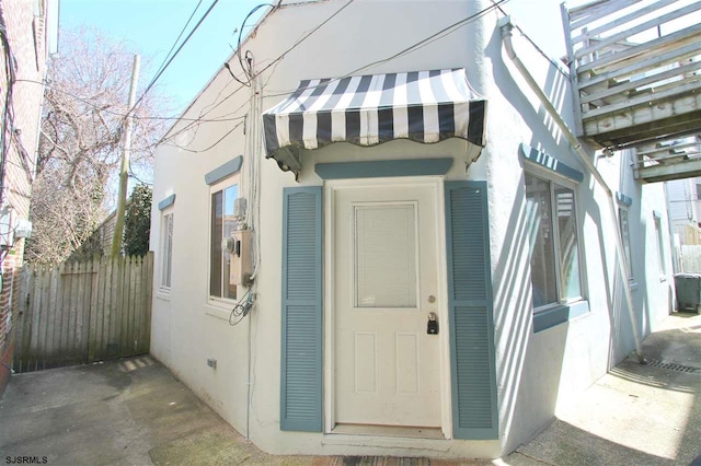 entrance to property with fence and stucco siding