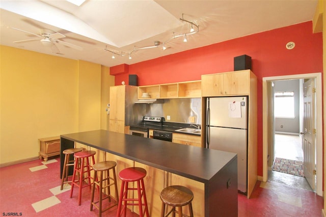 kitchen with a breakfast bar area, dark countertops, freestanding refrigerator, and stainless steel range with electric cooktop