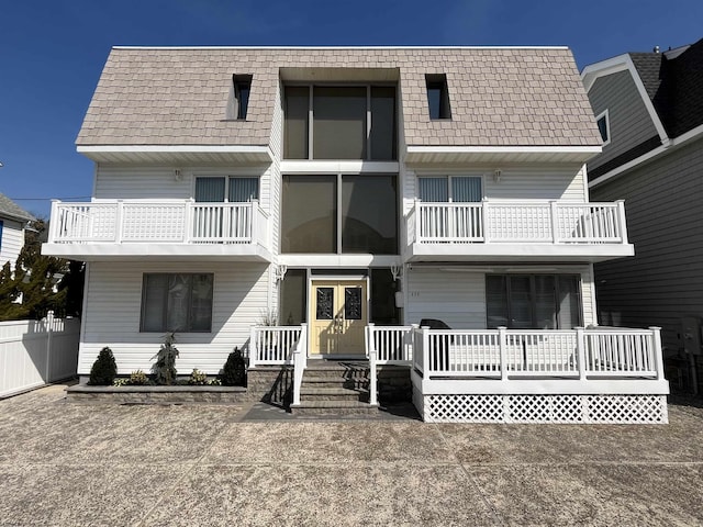 view of front of property with a balcony, fence, and french doors