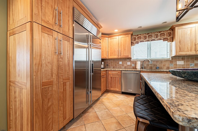 kitchen featuring stainless steel appliances, backsplash, light tile patterned flooring, and a sink