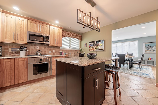 kitchen with stainless steel appliances, a center island, backsplash, and light tile patterned floors