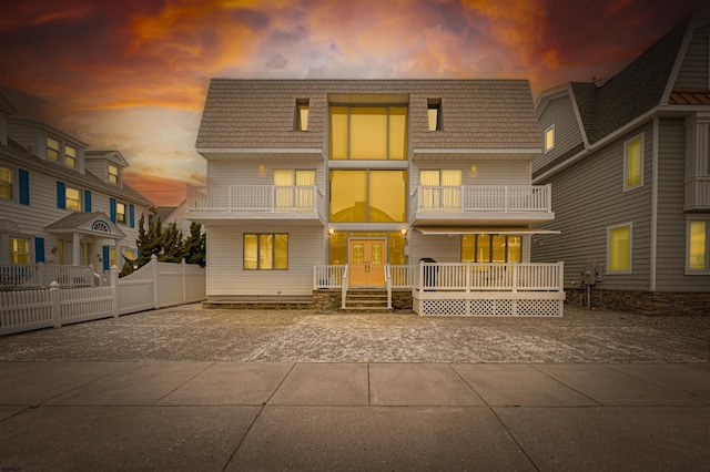 rear view of property featuring french doors, fence, and a balcony