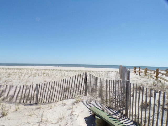 view of home's community featuring a view of the beach, a water view, and fence