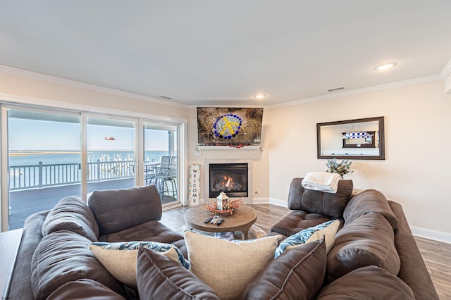 living area with crown molding, a fireplace, visible vents, wood finished floors, and baseboards