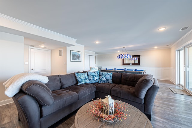 living area featuring ornamental molding, wainscoting, visible vents, and wood finished floors