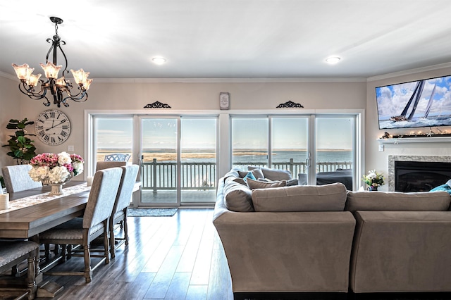 living area featuring a chandelier, ornamental molding, wood finished floors, and a glass covered fireplace