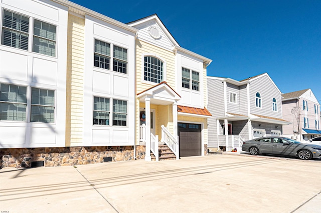 multi unit property with a garage, a residential view, and concrete driveway