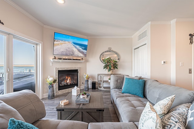 living room featuring a premium fireplace, wood finished floors, visible vents, baseboards, and ornamental molding