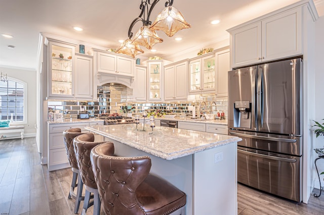 kitchen with ornamental molding, appliances with stainless steel finishes, wood finished floors, and decorative backsplash