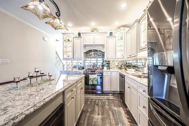 kitchen with light stone counters, dark wood-style floors, crown molding, stainless steel appliances, and backsplash