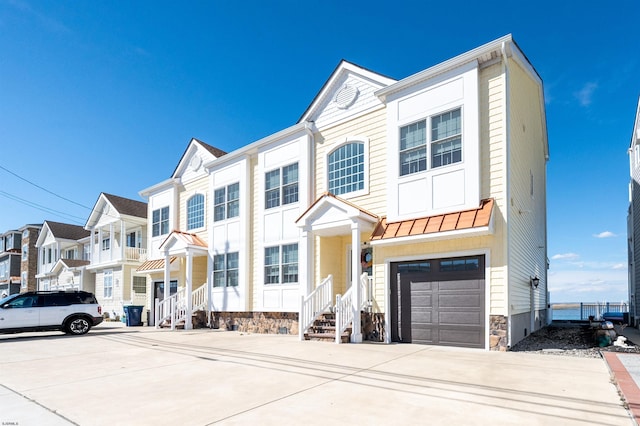 view of property featuring an attached garage, a standing seam roof, metal roof, a residential view, and driveway