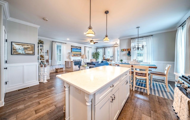 kitchen with a wealth of natural light, a fireplace, ornamental molding, and dark wood-style flooring