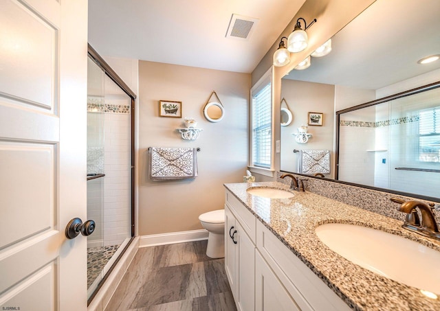 bathroom featuring toilet, a shower stall, visible vents, and a sink