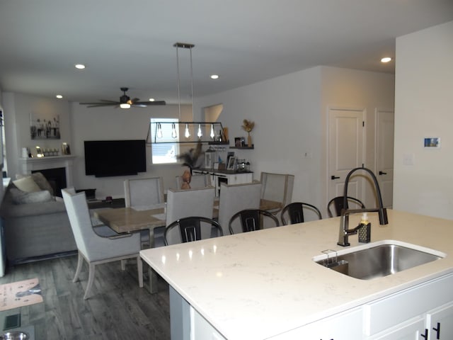 kitchen featuring dark wood finished floors, ceiling fan, a fireplace, a sink, and recessed lighting