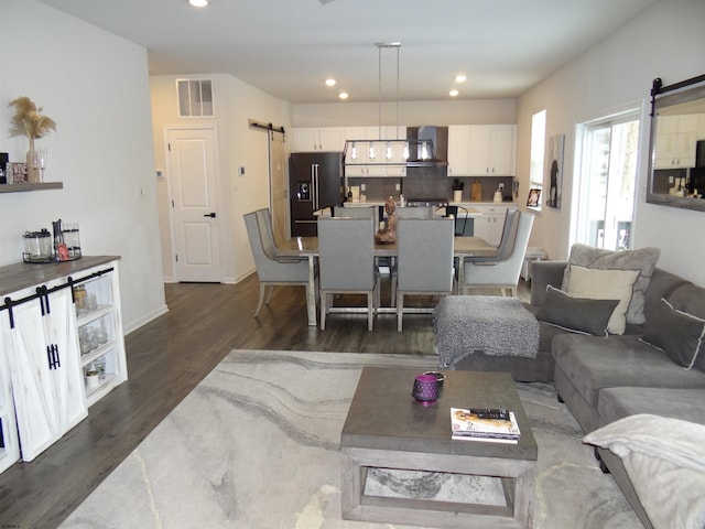 living area featuring a barn door, visible vents, dark wood finished floors, and recessed lighting