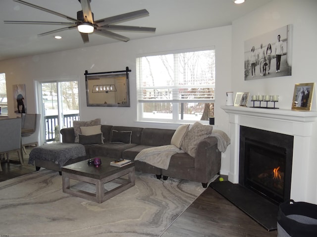 living area featuring a lit fireplace, ceiling fan, wood finished floors, and recessed lighting