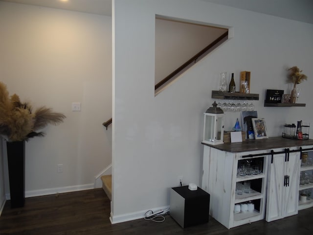 interior space with a dry bar, stairs, baseboards, and dark wood-style flooring