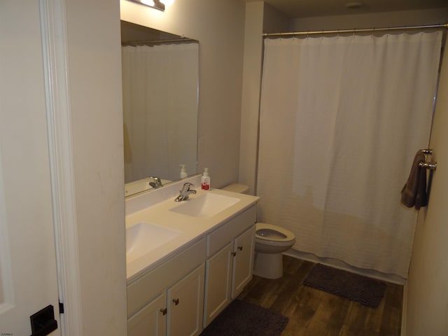 full bathroom with double vanity, a sink, toilet, and wood finished floors