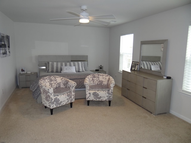 bedroom featuring light carpet, ceiling fan, multiple windows, and baseboards