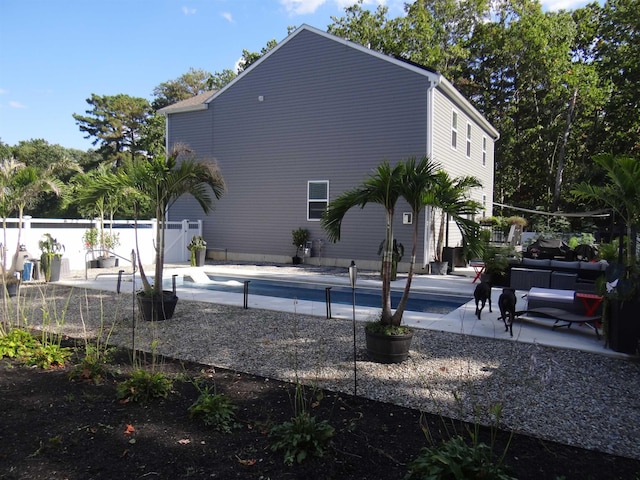 back of property with an outdoor pool, a patio area, and fence