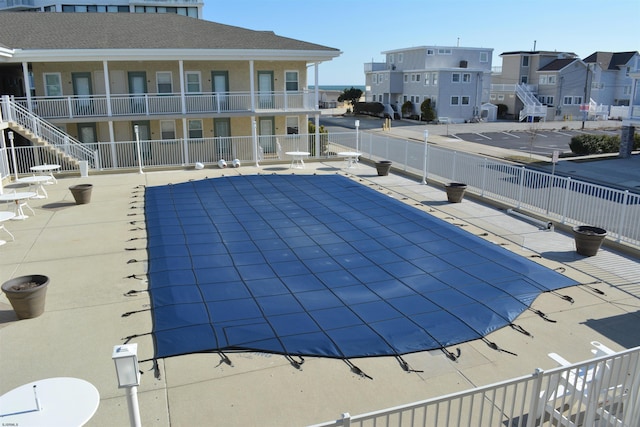 view of swimming pool with a patio area, fence, and a residential view