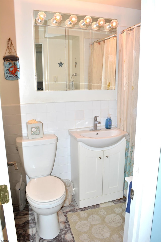 bathroom featuring a shower with shower curtain, vanity, toilet, and tile walls