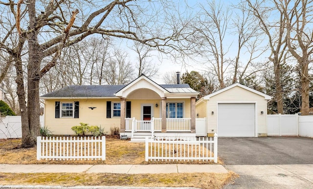 view of front of property with a porch, fence private yard, a garage, an outdoor structure, and driveway