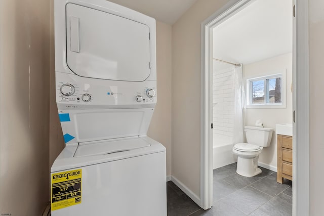 washroom featuring stacked washer / dryer, baseboards, and tile patterned floors