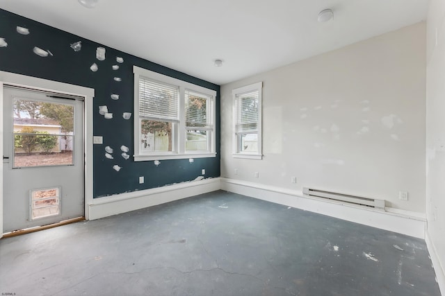 spare room with concrete flooring, baseboard heating, a wealth of natural light, and baseboards