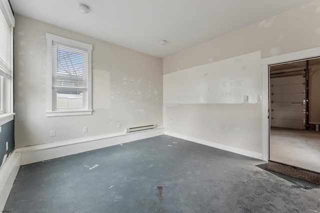 spare room featuring a baseboard heating unit and concrete floors