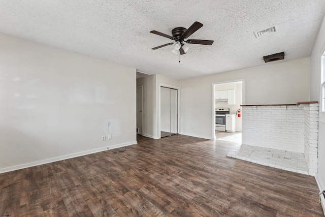 unfurnished living room with a textured ceiling, dark wood-type flooring, a ceiling fan, visible vents, and baseboards