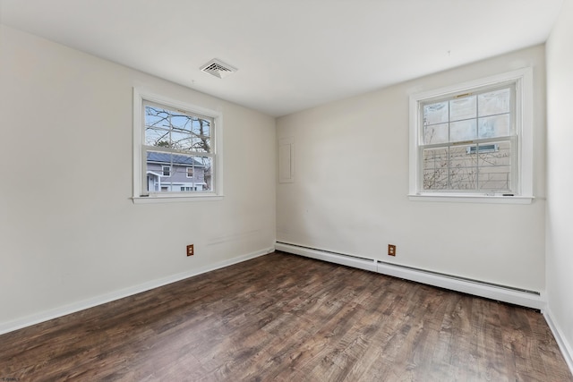 spare room with a baseboard radiator, wood finished floors, visible vents, and baseboards