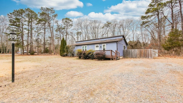 exterior space with driveway, fence, and a deck