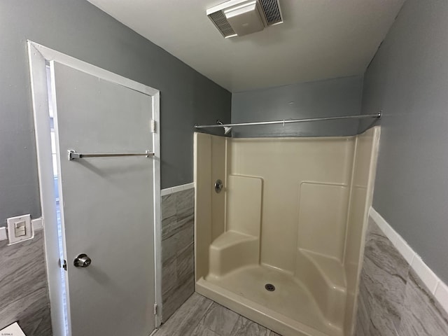 bathroom with baseboards, visible vents, and walk in shower