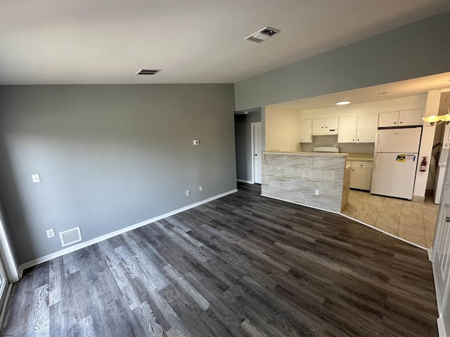 kitchen featuring visible vents, wood finished floors, freestanding refrigerator, and white cabinets