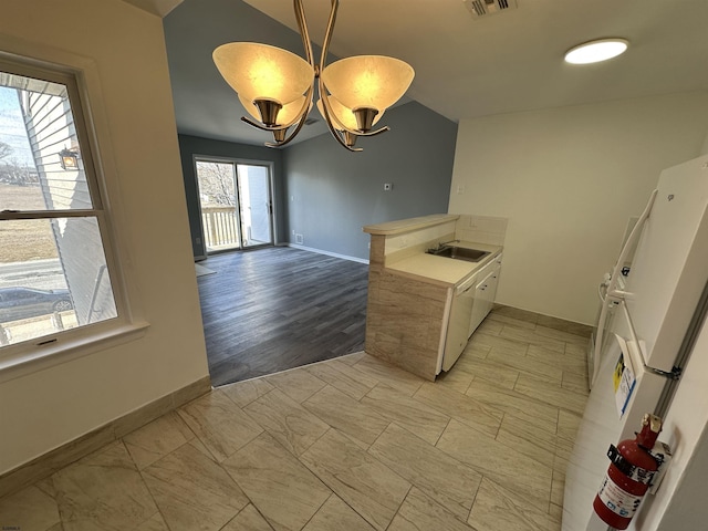 kitchen featuring an inviting chandelier, baseboards, visible vents, and a sink