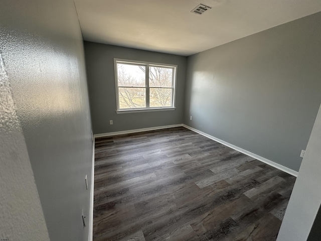 spare room with baseboards, visible vents, and dark wood-type flooring