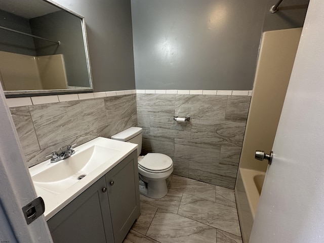 full bathroom featuring marble finish floor, wainscoting, vanity, and toilet