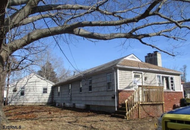 view of side of home with a chimney and brick siding