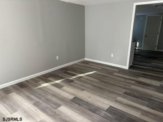 unfurnished room featuring dark wood finished floors and baseboards