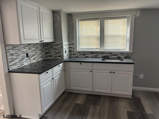 kitchen with dark countertops, a sink, and white cabinets