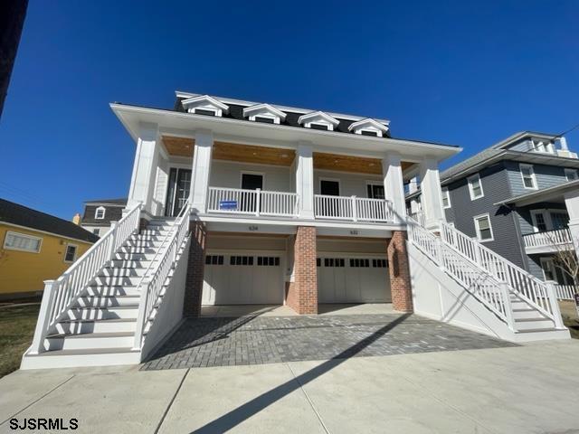 beach home featuring covered porch, driveway, stairway, and a garage