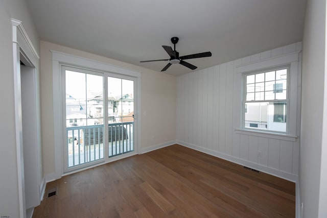 empty room with wood finished floors, visible vents, and a healthy amount of sunlight