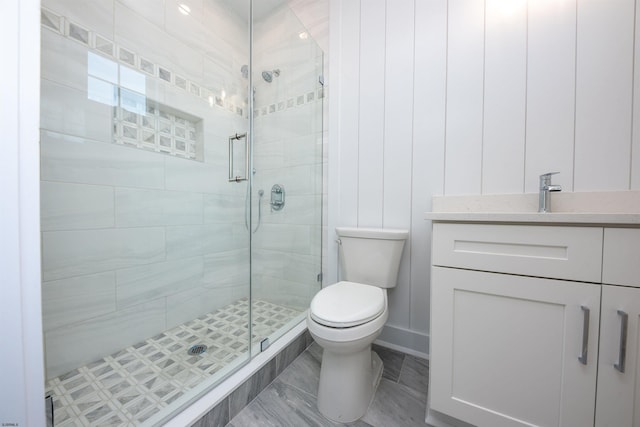 bathroom featuring toilet, a stall shower, and vanity