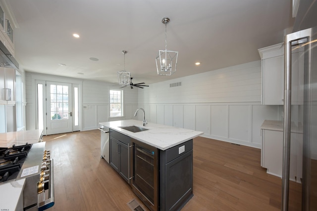 kitchen with beverage cooler, visible vents, wood finished floors, pendant lighting, and a sink