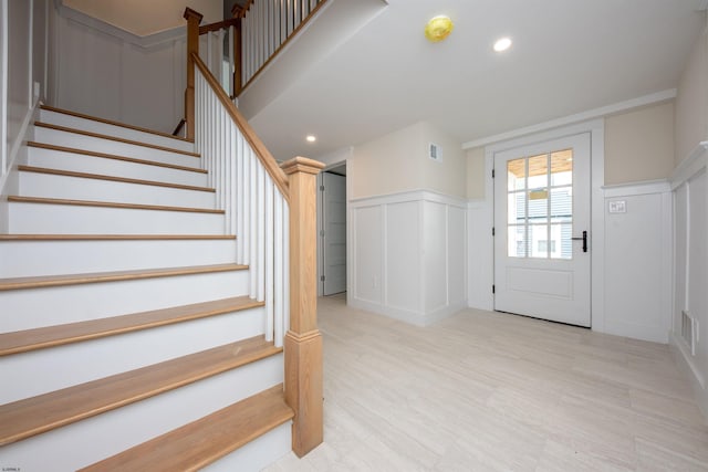 entrance foyer featuring recessed lighting, visible vents, a decorative wall, and stairway