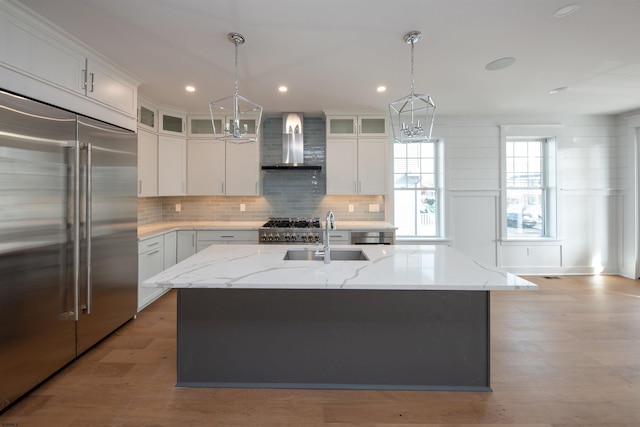 kitchen featuring built in fridge, a sink, wall chimney range hood, tasteful backsplash, and gas range oven